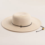 Ivory colored straw hat with a black band on a light beige background