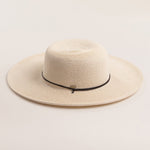 Ivory colored straw hat with a black band on a light beige background