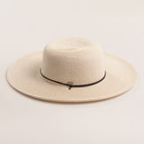 Ivory colored straw hat with a black band on a light beige background