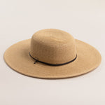 Natural colored straw hat with a wide brim on a light beige background