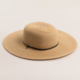 Natural colored straw hat with a wide brim on a light beige background