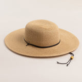 Natural colored straw hat with a wide brim on a light beige background
