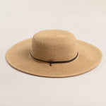 Natural colored straw hat with a wide brim on a light beige background