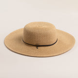 Natural colored straw hat with a wide brim on a light beige background