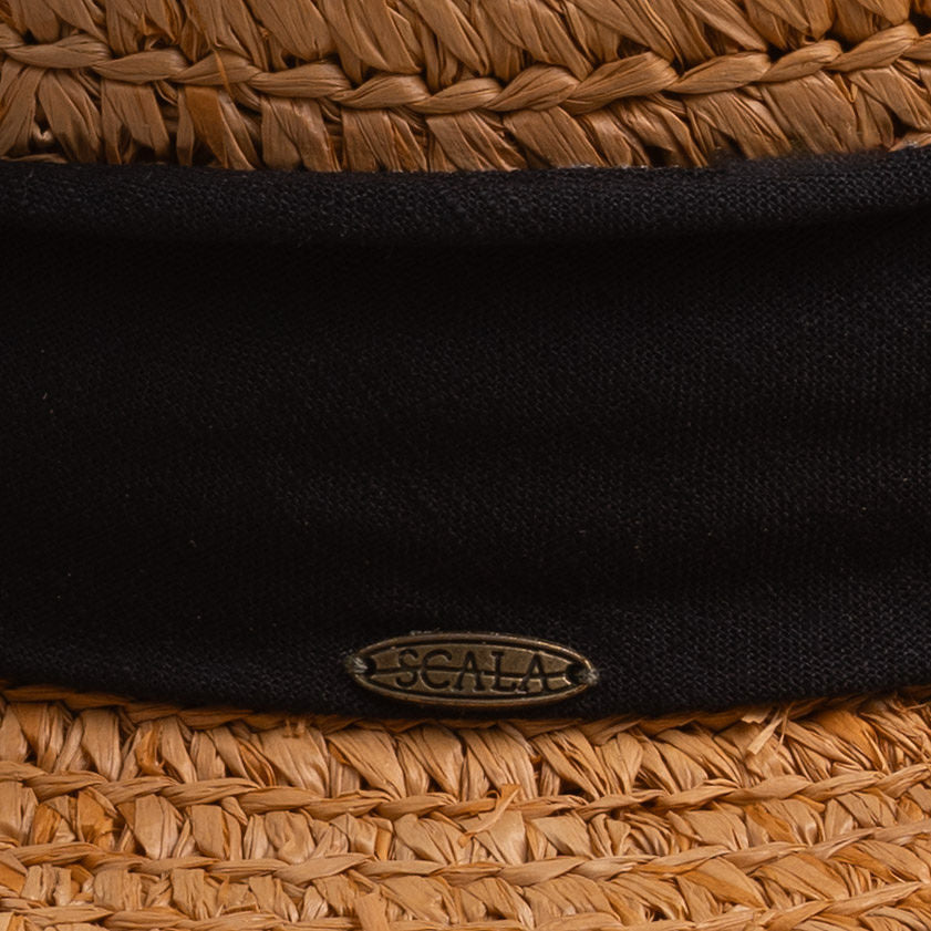 Close-up of a tea colored straw hat with a thick black ribbon and Scala logo pin on top of it