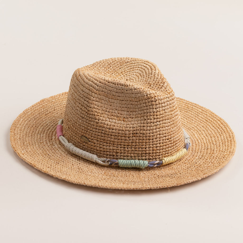 Natural colored straw hat with colorful and decorative band on a light beige background