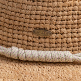 Close-up of a natural colored hat with a Scala logo pin and decorative rope-like band in dotted green, pink, gray, and white colors