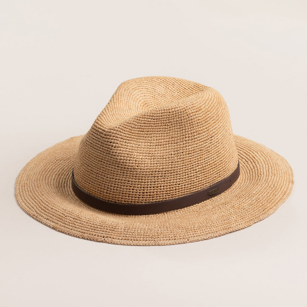 Natural colored straw hat with a brown band on a light beige background