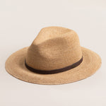 Natural colored straw hat with a brown band on a light beige background