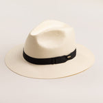 Natural colored straw hat with a black band on a light beige background