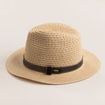 Natural colored straw hat with a brown band on a light beieg background