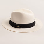 Natural colored straw hat with a black band on a light beige background