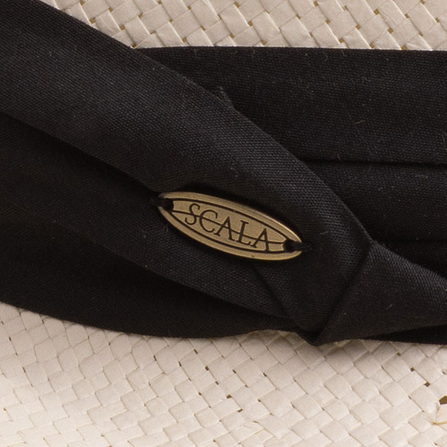 Close-up of a natural color straw hat with black band and Scala logo pin on top of it