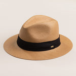 Putty colored straw hat with a black band on a light beige background