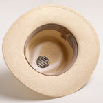 Underside of a natural colored straw hat with a light brown sweatband on a light gray background
