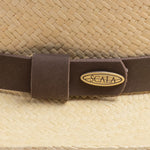 Close-up of a natural colored Panama hat with a brown band featuring the Scala logo pin on top of it