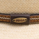 Close-up of a natural colored straw hat with a brown band and the Scala logo pin on top of it