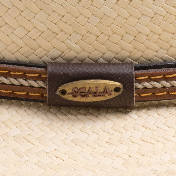 Close-up of a natural colored straw hat with a brown band and the Scala logo pin on top of it