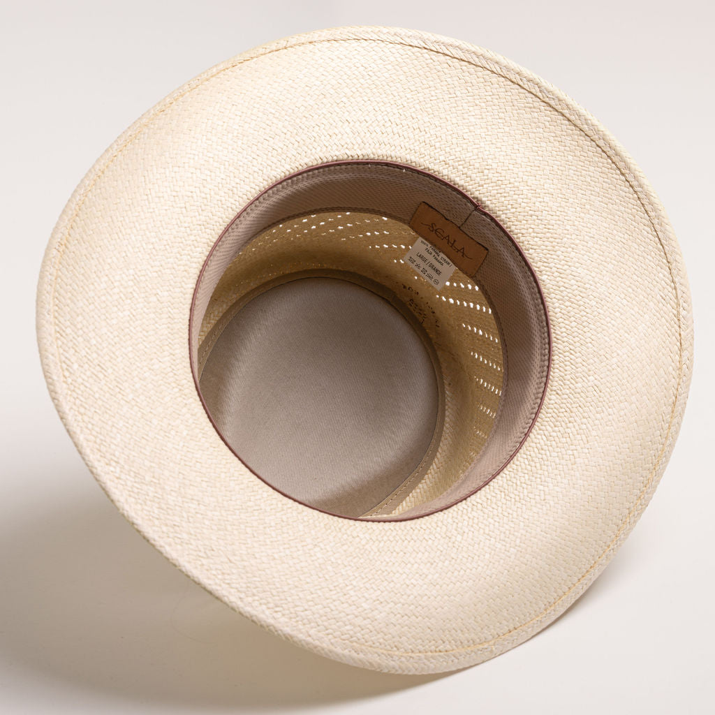 Underside of a natural colored straw hat with a light brown sweatband on a light gray background