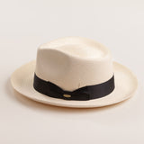 Bleach colored Panama hat with a thick black band on a light beige background