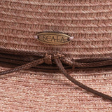 Close-up of a blush colored straw hat with a knotted string and Scala logo pin