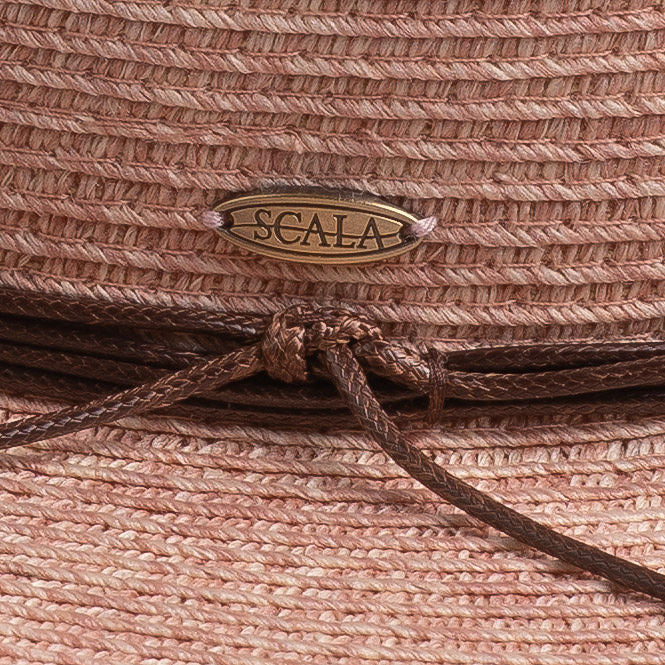 Close-up of a blush colored straw hat with a knotted string and Scala logo pin