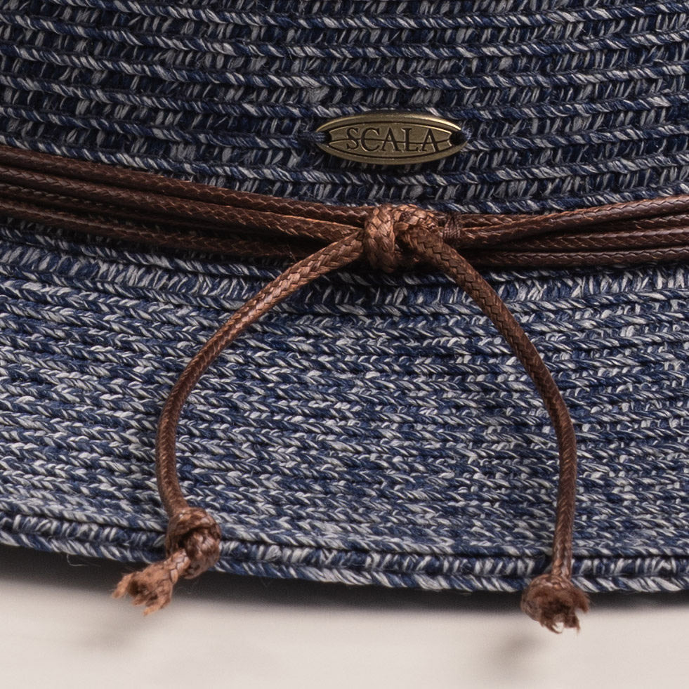 Close-up of a denim colored straw hat with a knotted string and Scala logo pin