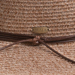 Close-up of a taupe colored straw hat with a knotted string and Scala logo pin