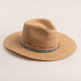 Natural colored straw hat with a decorative band on a light beige background