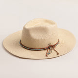 Natural colored straw hat with a decorative band on a light beige background
