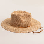 Natural colored straw hat with a brown band on a light beige background