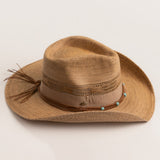 Tea colored straw-shaped cowboy hat with decorative band with turquoise beads on a light beige background