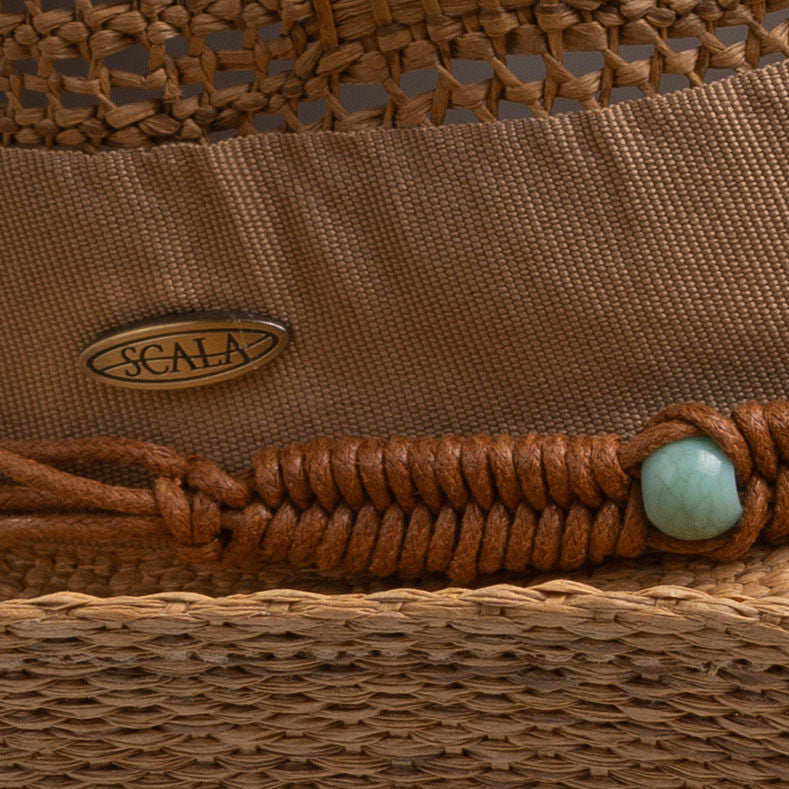 Close-up of a tea colored cowboy-shaped straw hat with braided band detail, turquoise bead, and Scala logo pin