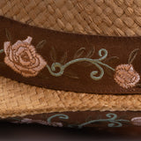 Close-up of a tea colored straw hat with embroidered floral band and underbrim