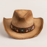 Tea colored straw cowboy-shaped hat with decorative floral pattern band and underbrim on a light beige background