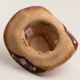 Underside of a tea colored straw cowboy-shaped hat with decorative floral pattern underbrim on a light beige background