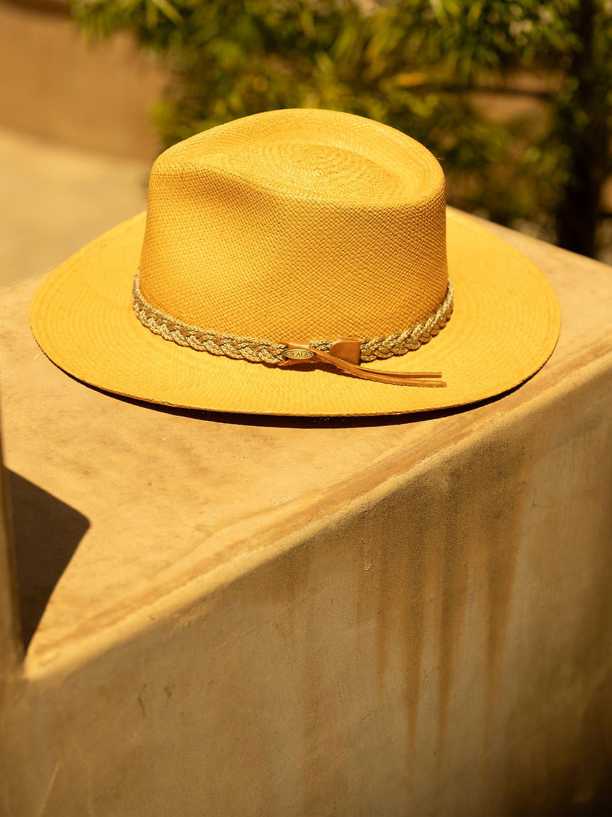 Putty colored Panama hat with a decorative band on a stone surface